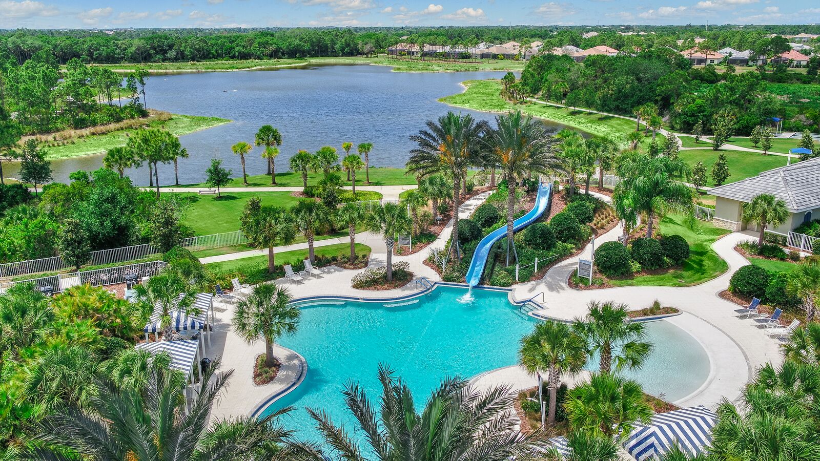 Aerial view of Grand Palm amenity center with resort pool, water slide, and lakefront tropical landscape